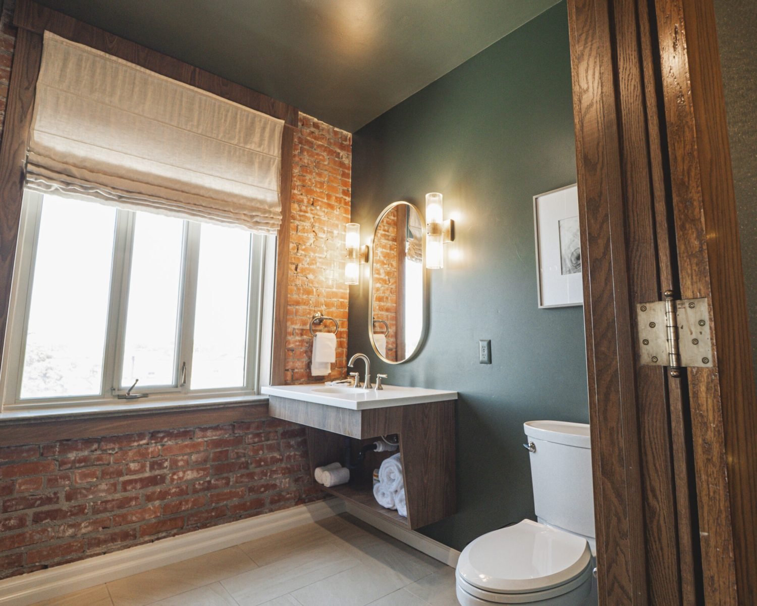 the-ford-suite-bathroom-exposed-brick-window-soft-green-walls-modern-vanity-lighting-powerhouse-on-broadway