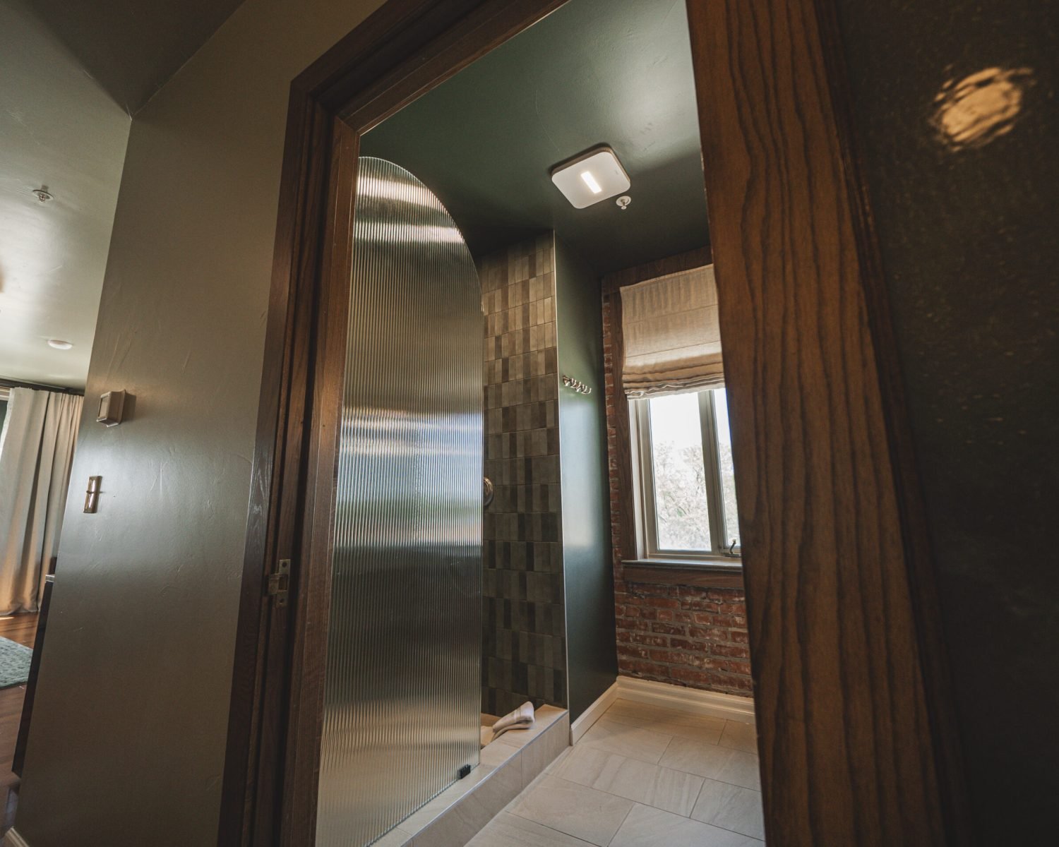 the-ford-suite-bathroom-tiled-shower-exposed-brick-window-soft-green-walls-modern-lighting-powerhouse-on-broadway