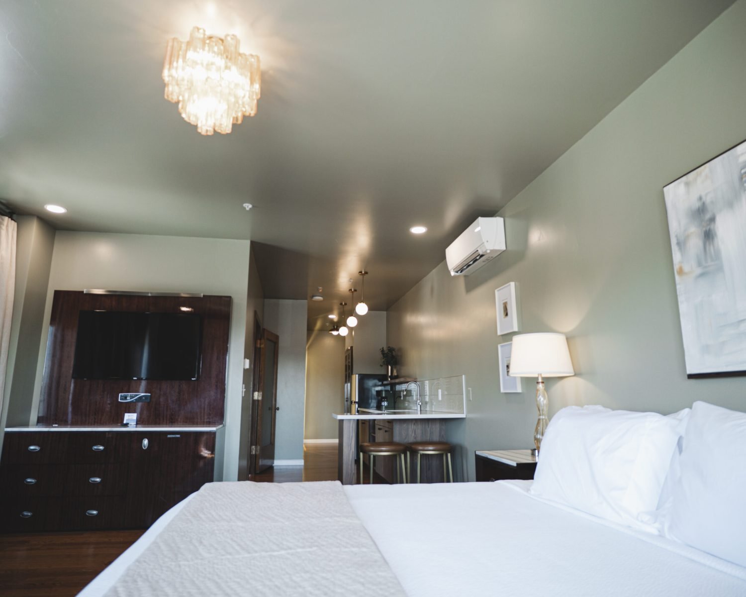 the-ford-suite-full-room-view-soft-green-walls-crystal-chandelier-kitchenette-tv-unit-powerhouse-on-broadway