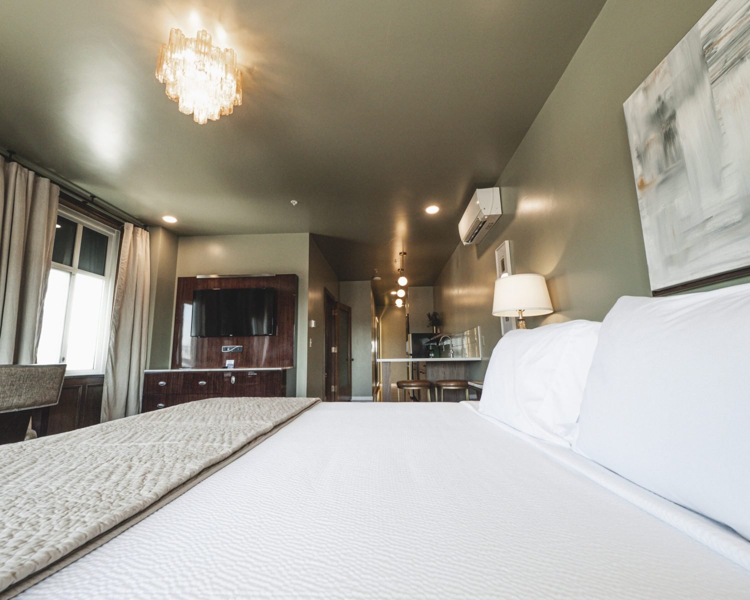 the-ford-suite-low-angle-bed-view-soft-green-walls-artwork-kitchenette-lighting-powerhouse-on-broadway